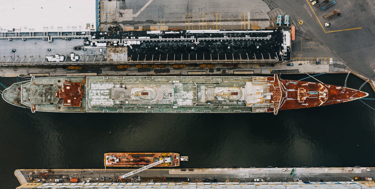 Drone view of long ship moored on water of river near pier in daytime